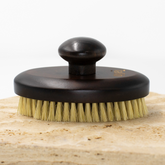 Brass brush with wooden handle on a wooden block against a white background