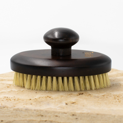 Brass brush with wooden handle on a wooden block against a white background