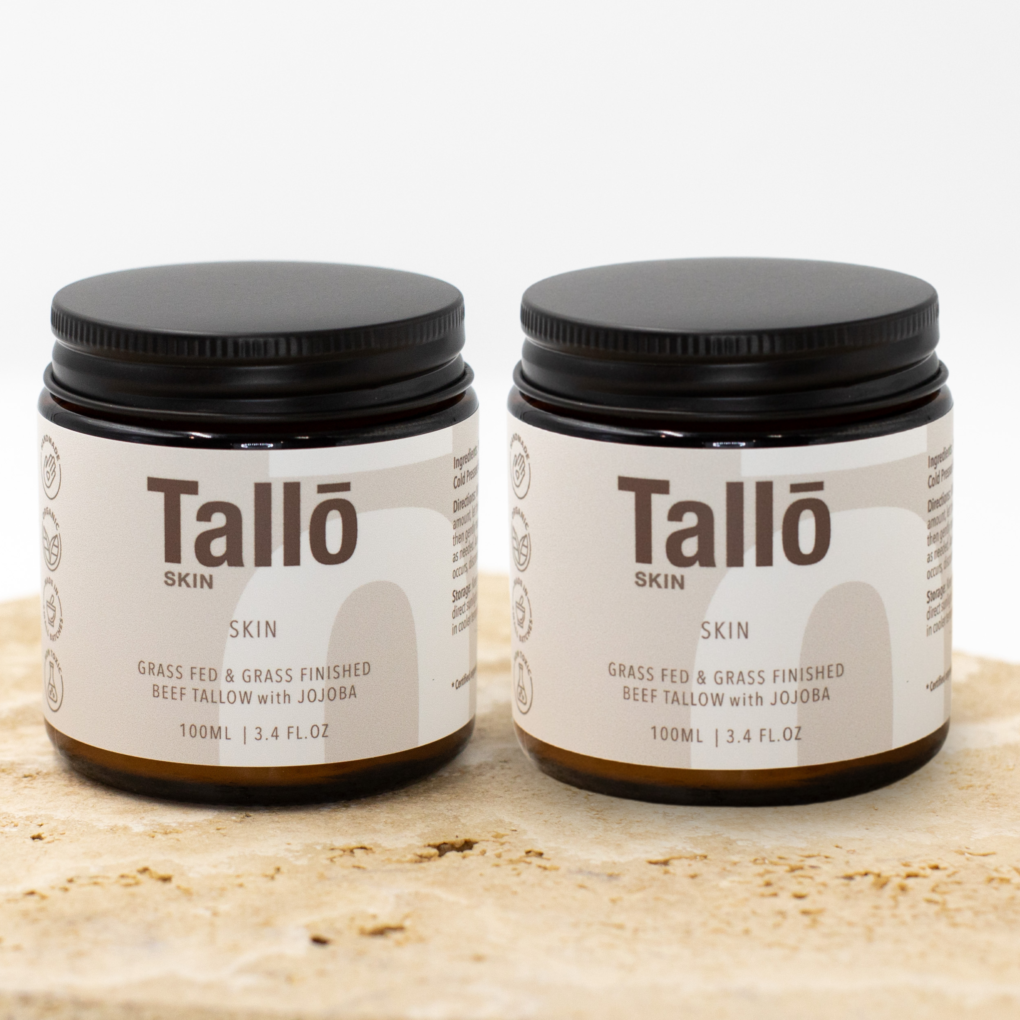 Two jars of Talló Skin on a wooden surface