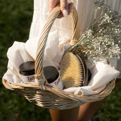 Person holding a basket with skincare products and natural elements outdoors