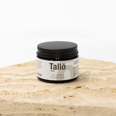 Jar of Tallow balm on a stone surface with a white background