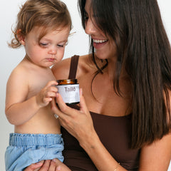 Woman and child holding a jar of Tallo product against a plain background