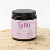 Jar of Tallo Skin cream with a pink label on a light brown surface